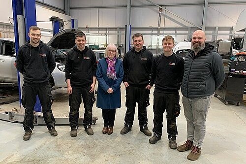 Beatrice stands with apprentices at Shetland MOT & Repair, Tingwall