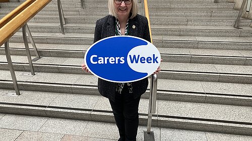 Beatrice Wishart holding a Carers Week sign.